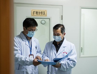 沈谨(右)在宿迁疾病预防控制中心实验室前审核病毒检测报告