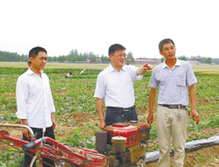 魏華偉（中）在村草莓種植基地和村民商量下一步發展大計。 魏剛攝
