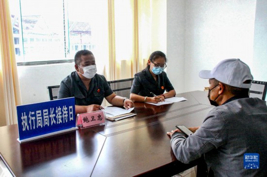 執行局局長接待日，鮑衛忠（左）在雲南省滄源佤族自治縣人民法院執行指揮中心接待案件當事人（2020年6月18日攝）。新華社發